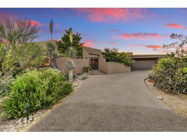 Stunning home exterior featuring desert landscaping and an inviting entryway at sunset at 10638 E Honey Mesquite Dr, Scottsdale, AZ 85262