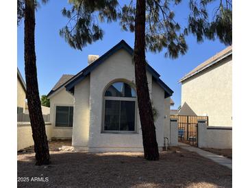 Charming single-story home featuring a stucco facade, blue trim, and a manicured front yard with mature trees at 1535 N Horne St # 62, Mesa, AZ 85203