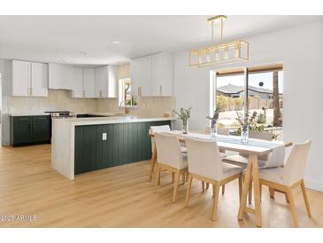Bright kitchen features white cabinets with gold hardware, an island, and a dining area with a window view at 18428 N 42Nd St, Phoenix, AZ 85032