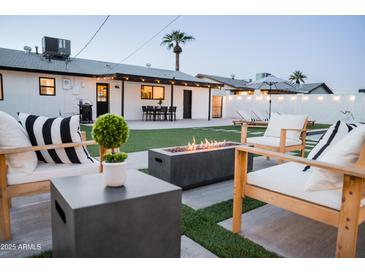Cozy backyard featuring a modern fire pit, outdoor seating, and a well-manicured lawn with string lights at 2023 N 79Th Pl, Scottsdale, AZ 85257