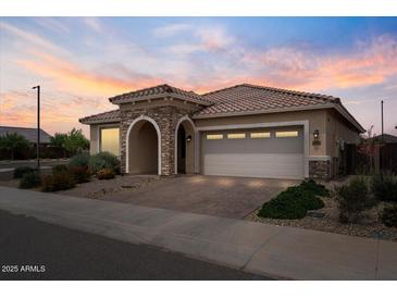 Charming single-story home featuring a two-car garage, and stone accents at the entrance, complemented by well-maintained landscaping at 25030 N 172Nd Ln, Surprise, AZ 85387