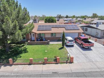 Charming single-story home featuring solar panels, a well-manicured lawn, and a spacious driveway at 3107 N 79Th Ave, Phoenix, AZ 85033