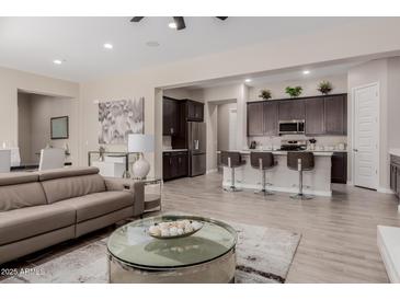 Open-concept living room and kitchen with a comfortable couch and modern bar stools at 3852 E Bartlett Way, Chandler, AZ 85249