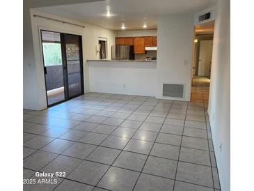 Open-concept living room featuring tile floors, sliding glass doors, and a breakfast bar overlooking the kitchen at 533 W Guadalupe Rd # 2126, Mesa, AZ 85210