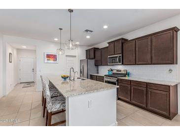 An updated kitchen features a granite island, stainless steel appliances, and tile flooring at 607 W Tenia Trl, San Tan Valley, AZ 85140