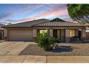 Charming single-story home featuring a tile roof, stone accents, covered porch and desert landscaping at 9632 E Olla Ave, Mesa, AZ 85212