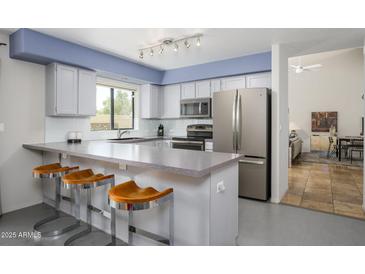 Bright kitchen boasts stainless steel appliances, ample counter space, and stylish bar seating at 1124 E Rose Ln # 17, Phoenix, AZ 85014