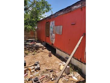 Shows the rundown exterior of a mobile home with peeling paint and boarded up windows in disrepair at 1416 E Southern Ave, Apache Junction, AZ 85119