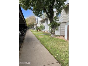 Inviting exterior view of the townhouse complex, showcasing well-maintained landscaping and charming architecture at 2530 W Berridge Ln # E111, Phoenix, AZ 85017