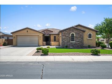 Charming single-story home with a two-car garage and stone accents, showcasing manicured landscaping and inviting curb appeal at 4721 N Aldea W Rd, Litchfield Park, AZ 85340