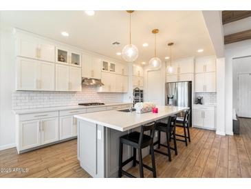Modern kitchen featuring white cabinets, quartz countertops, subway tile backsplash, and a large island with bar seating at 4050 S Thistle S Dr, Chandler, AZ 85248
