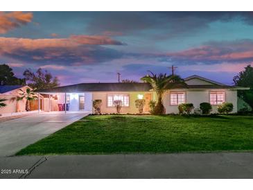 Charming single-story home featuring a lush green lawn, covered parking, and manicured landscaping at 6901 E Oak St, Scottsdale, AZ 85257