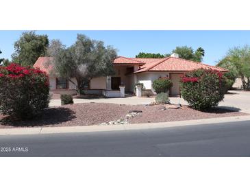 Charming single-story home featuring a tile roof, desert landscaping, and mature trees at 6940 W Willow Ave, Peoria, AZ 85381