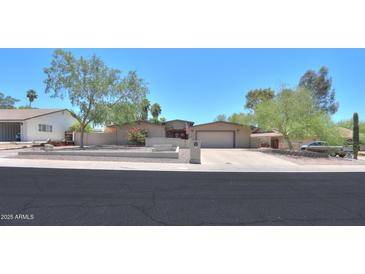 Charming single-story home featuring a large driveway, desert landscaping, and an American flag proudly displayed at 511 E Port Au Prince Ln, Phoenix, AZ 85022