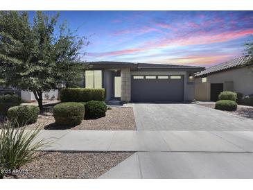 Charming single-story home featuring a paved driveway, landscaped front yard, and attached two-car garage at 14393 W Wethersfield Rd, Surprise, AZ 85379
