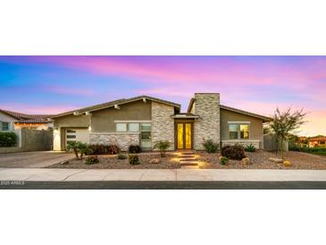 Charming single-story home featuring stone accents, manicured landscaping, and a welcoming illuminated entryway at 13820 W Weaver Ct, Litchfield Park, AZ 85340