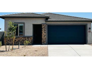 Charming single-story home featuring a blue garage door, stone accents, and a well-maintained front yard at 25133 W Wayland Dr, Buckeye, AZ 85326