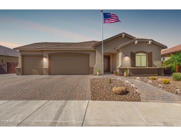 Beautiful home with a three car garage, a brick driveway and a manicured, desert landscaped yard at 1036 W Siebold Tree Ave, Queen Creek, AZ 85140