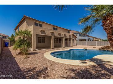 Backyard oasis with sparkling pool, lush palms, and covered patio, ideal for relaxation and entertaining at 11511 E Renata Ave, Mesa, AZ 85212