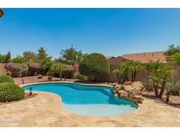 Backyard pool with lush landscaping and rock waterfall feature at 3331 N Acacia Way, Buckeye, AZ 85396