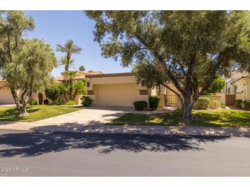 Charming single-story home featuring a well-manicured lawn and a two-car garage at 10429 N 101St St, Scottsdale, AZ 85258