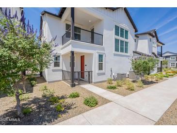 Charming townhome with a red door, black accents, balcony, and manicured landscaping at 11300 N Casa Dega Dr # 1005, Surprise, AZ 85388