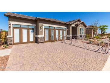 Charming single-story home boasting a stylish facade with stone accents and a paved driveway under a clear blue sky at 27647 N 176Th Dr, Surprise, AZ 85387