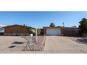Charming single story home with a brick facade, low maintenance desert landscaping, and a driveway leading to a single garage at 2933 W Del Mar Ln, Phoenix, AZ 85053