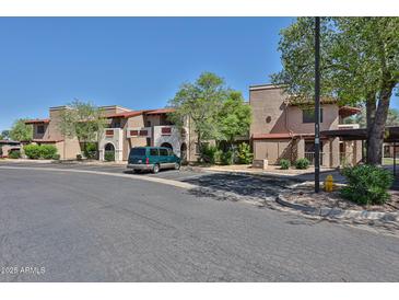 Condominium building with covered parking and mature trees on a sunny day with blue sky at 5757 W Eugie Ave # 2068, Glendale, AZ 85304