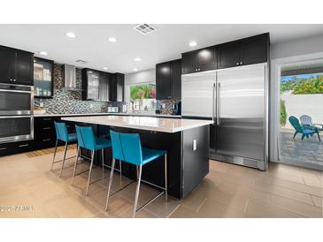 Modern kitchen features dark cabinetry, a large island with seating, and stainless steel appliances at 7533 N 8Th St, Phoenix, AZ 85020