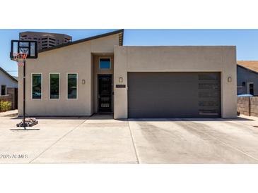 Modern home featuring a contemporary design, gray garage door, and a basketball hoop in the driveway at 1005 E Weldon Ave, Phoenix, AZ 85014