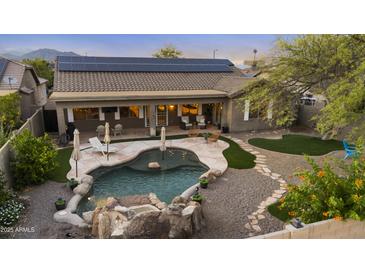 Beautiful backyard featuring a pool with rock waterfall, lounging area, and desert landscaping at 22205 W Ashleigh Marie Dr, Buckeye, AZ 85326