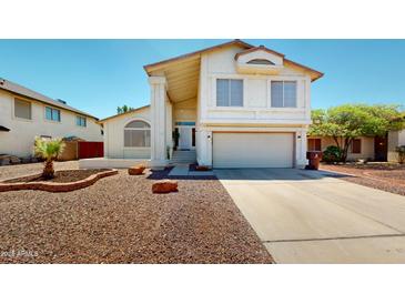 Inviting two-story home featuring a spacious driveway, desert landscaping, and a charming front porch entrance at 8541 W Pershing Ave, Peoria, AZ 85381