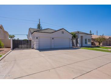 Home exterior showcasing the driveway, a two-car garage, and black-tiled roofing against a brilliant blue sky at 1062 N Robin Ln, Mesa, AZ 85213
