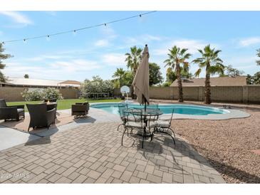 Inviting backyard featuring a refreshing pool, outdoor seating, and mature palm trees for a perfect oasis at 1406 E Jasper Dr, Chandler, AZ 85225
