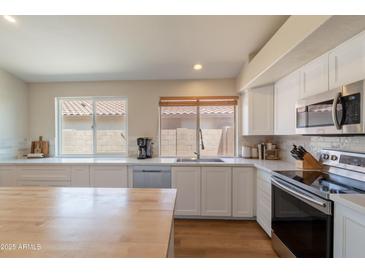 Bright kitchen featuring wood-top island and white cabinets at 15128 W Melissa Ln, Surprise, AZ 85374
