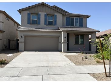 Two-story home showcasing a grey exterior, brown garage door, blue shutters and a well maintained lawn at 18361 W Jessie Ln, Surprise, AZ 85387