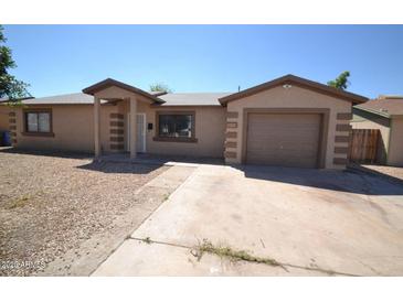 Cozy single-story home showcasing a desert landscape, attached garage, and covered porch entryway at 2036 N 64Th Ln, Phoenix, AZ 85035