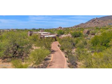Expansive exterior view of a modern home with desert landscaping, and a long private drive on a sunny day at 35180 N Boulder Pass, Scottsdale, AZ 85266