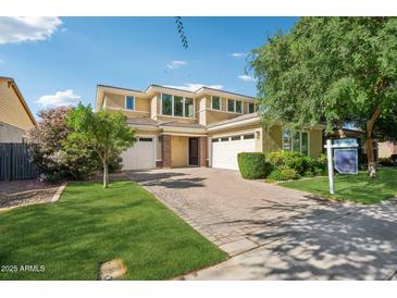 Charming two-story home featuring a paver driveway, lush landscaping, and a three-car garage at 4109 E Sierra Madre Ave, Gilbert, AZ 85296