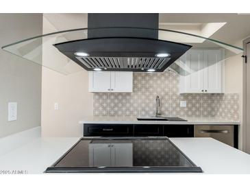 Close-up of the kitchen featuring sleek black vent hood, modern backsplash, and stainless steel appliances at 4228 N 81St St, Scottsdale, AZ 85251