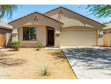 Charming single-story home with a low-maintenance desert-style front yard and attached two-car garage at 7365 W Magdalena Ln, Laveen, AZ 85339