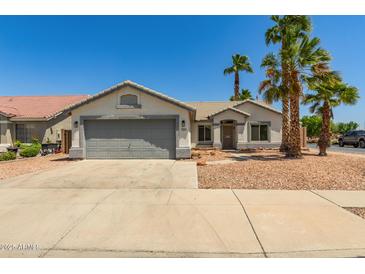Charming single-story home with a gray two-car garage, desert landscaping, and mature palm trees at 7924 W Hammond Ln, Phoenix, AZ 85043