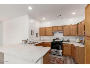 A bright kitchen features wooden cabinetry, quartz countertops, and stainless steel appliances at 11182 W Coronado Rd, Avondale, AZ 85392