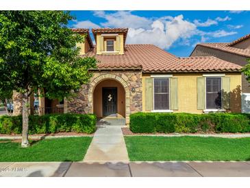 Charming home featuring a stone archway, lush green lawn and well-manicured hedges at 1134 S Lydia Ln, Gilbert, AZ 85296