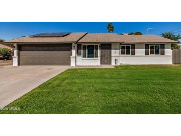 Charming single-story home with a well-manicured lawn and a two-car garage, complemented by solar panels at 1906 N Evergreen St, Chandler, AZ 85225