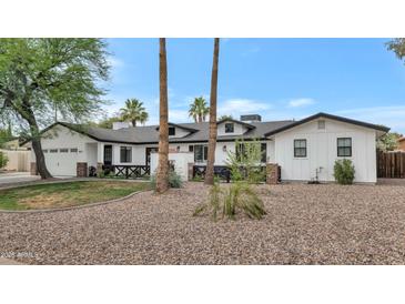 Beautifully renovated home featuring a white painted exterior, dark trim, and mature landscaping at 5612 E Emile Zola Ave, Scottsdale, AZ 85254