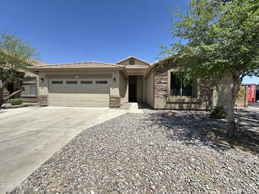 Charming single story home featuring a two-car garage, desert landscaping, and stone accents at 7419 S 45Th Ave, Laveen, AZ 85339