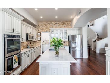 Bright kitchen features white cabinetry, stainless appliances, brick backsplash and large island at 15240 N Clubgate Dr # 160, Scottsdale, AZ 85254