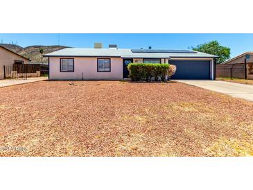 Charming single-story home featuring a gravel yard, solar panels, and an attached two-car garage at 1733 W Surrey Ave, Phoenix, AZ 85029